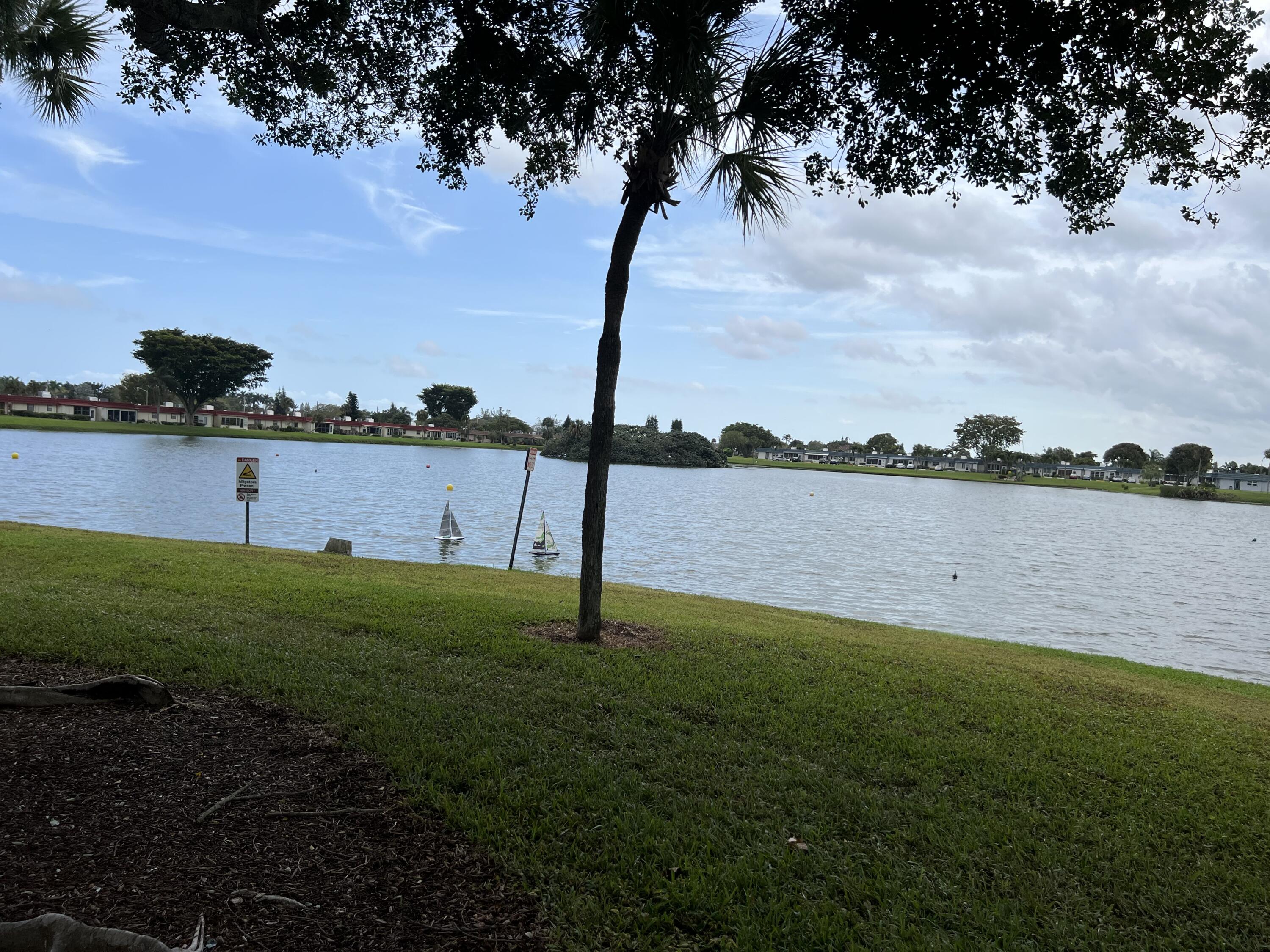 183 Normandy Lane Delray Beach, FL 33484 - Photo 56 of 80 a view of a lake with a big yard and potted plants
