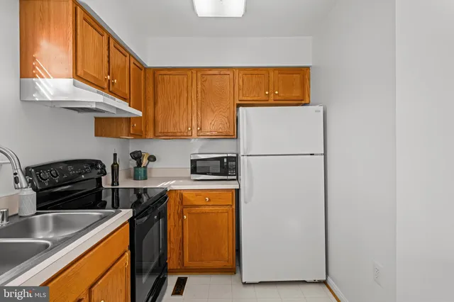 a kitchen with stainless steel appliances granite countertop a refrigerator a stove a sink and a white cabinets