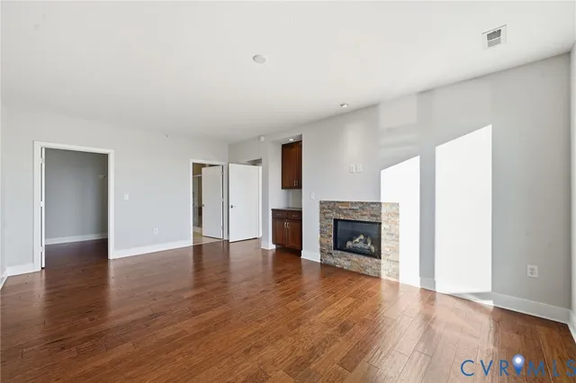 a view of an empty room with wooden floor and a fireplace