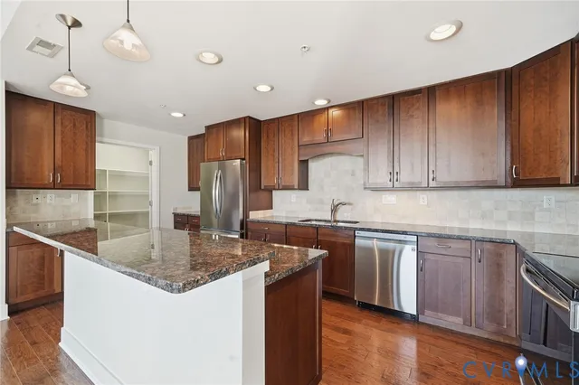 a kitchen with stainless steel appliances granite countertop a sink stove and wooden floor