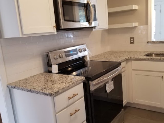 1210 Dearing Road Memphis, TN 38117 - Photo 10 of 25 The beautiful new kitchen features new white cabinetry with soft close doors/drawers, granite, new tile flooring, and a solid-surface electric stove & built-in microwave!