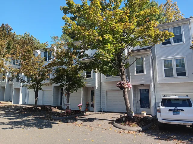 a front view of a house with a tree in front