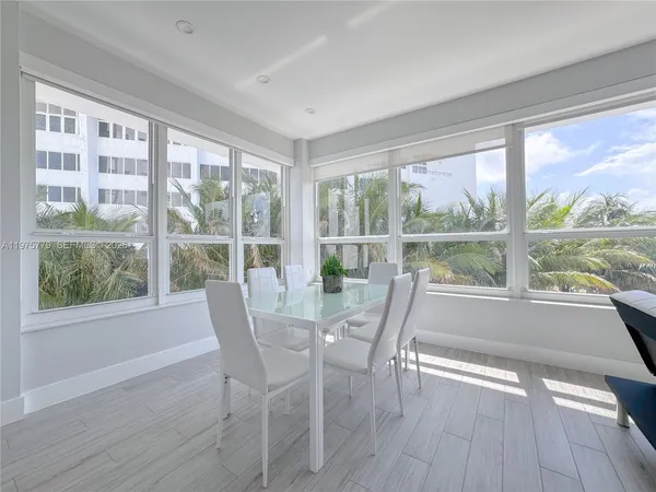 a dining room with wooden floor a glass table and windows