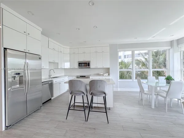 a kitchen with stainless steel appliances a dining table chairs refrigerator and sink