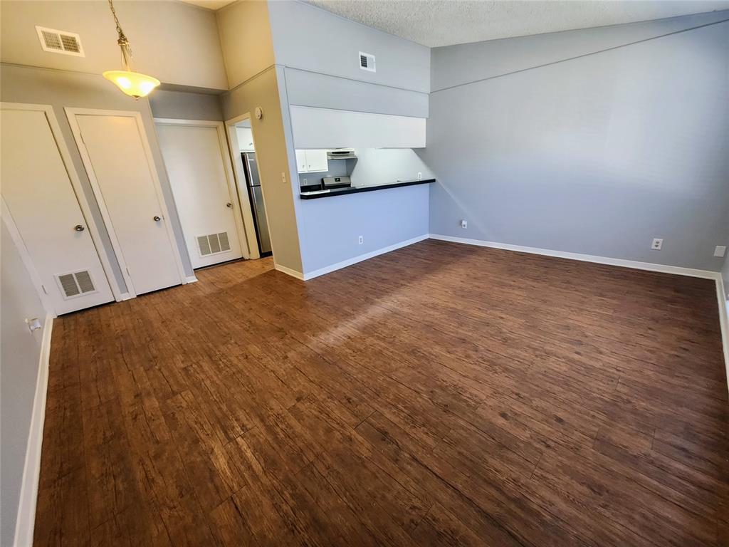608 West 51st Street, Unit 101 Austin, TX 78751 - Photo 2 of 11 Unfurnished living room featuring dark wood-style floors and a textured ceiling