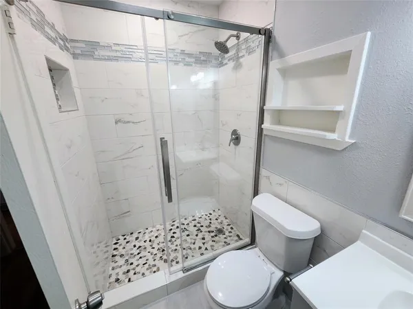 a white toilet sitting next to a shower