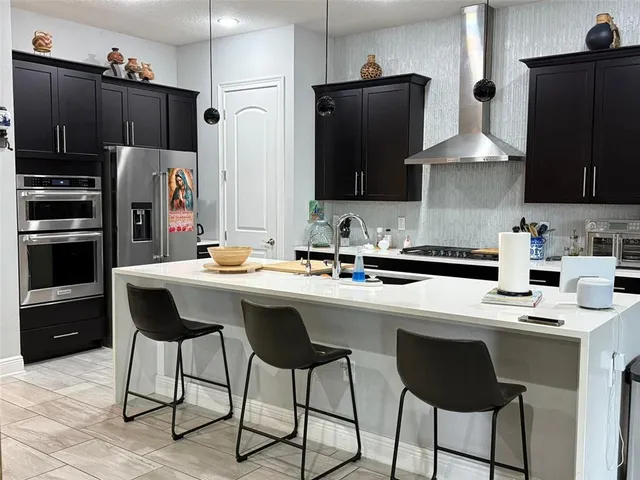 a kitchen with stainless steel appliances granite countertop a refrigerator and a stove top oven
