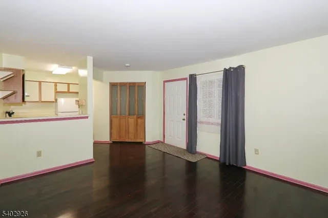 a view of an empty room with wooden floor and cabinet