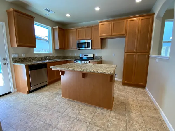 a kitchen with stainless steel appliances granite countertop a stove a sink dishwasher a refrigerator and a microwave