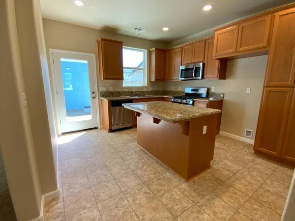 a kitchen with stainless steel appliances granite countertop a stove a refrigerator a sink a microwave and island
