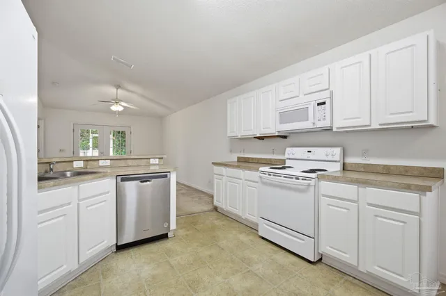 a kitchen with white cabinets and white appliances
