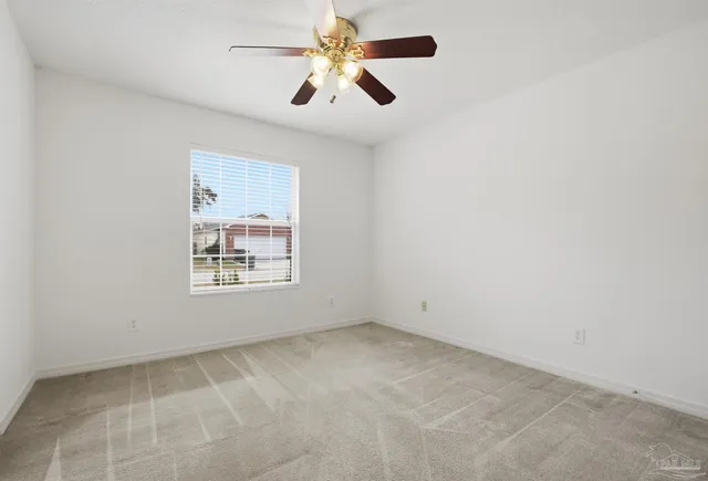 an empty room with ceiling fan and window