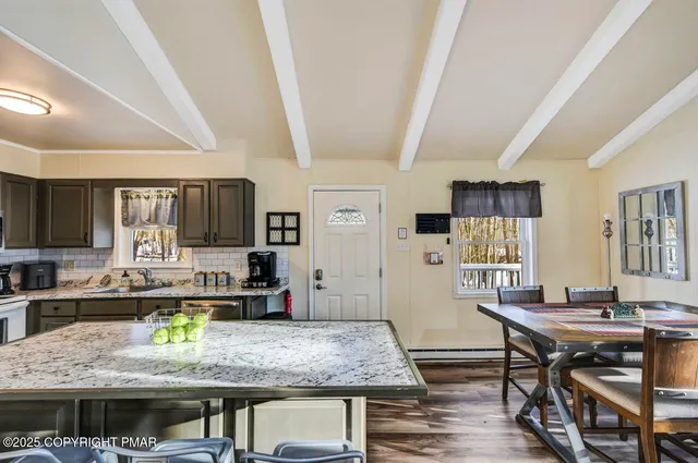 a kitchen with stainless steel appliances granite countertop a stove top oven a sink a dining table and chairs with wooden floor