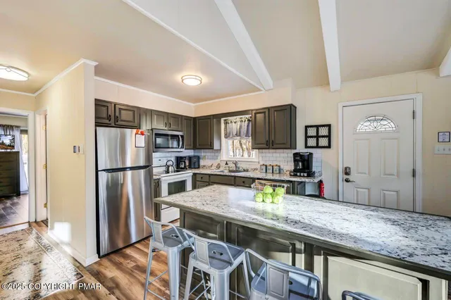 a kitchen with a stove a sink dishwasher a dining table and chairs with wooden floor