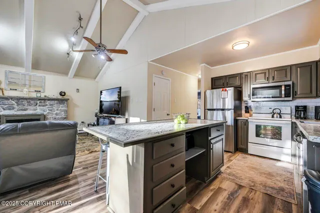 a kitchen with a stove a sink dishwasher a dining table and chairs with wooden floor