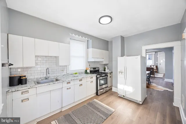 a kitchen with a refrigerator a stove top oven a sink and cabinets