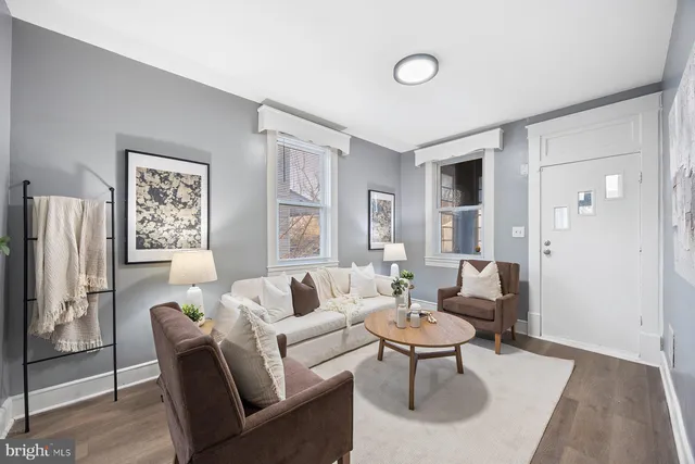 a living room with furniture a large window and a refrigerator