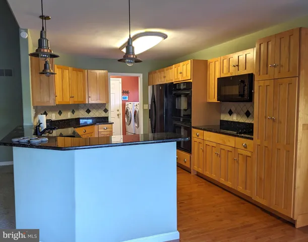 a kitchen with granite countertop a sink cabinets and stainless steel appliances