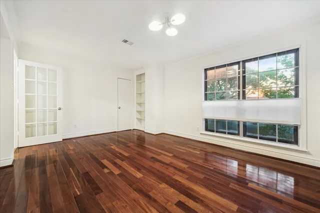 a view of empty room with wooden floor and fan