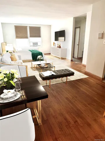 a living room with stainless steel appliances furniture a rug and a window