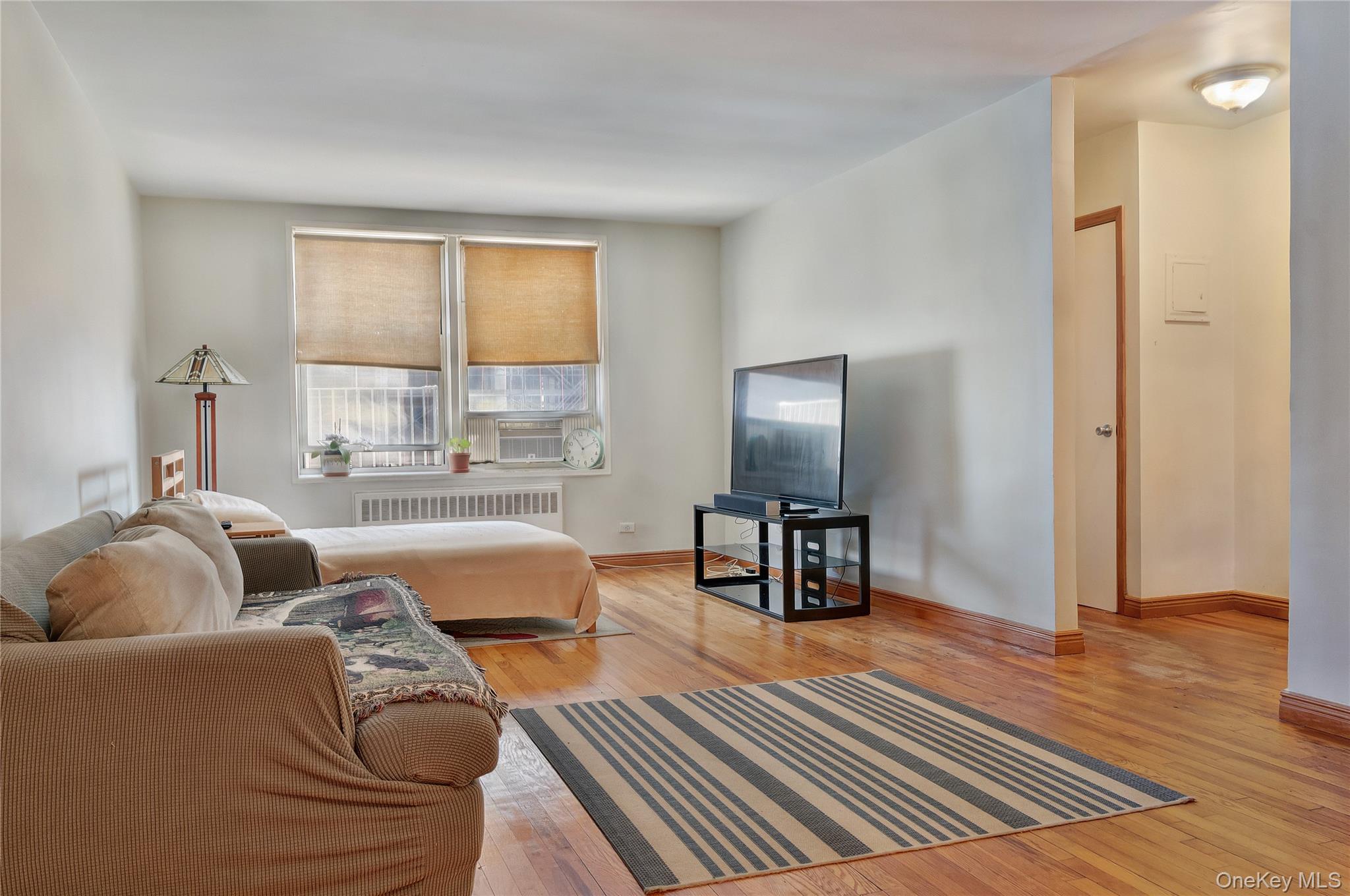 133 Beach 120th Street, Unit 2C Queens, NY 11694 - Photo 5 of 13 a living room with furniture and a flat screen tv
