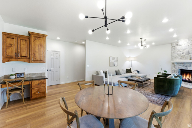 1712 Somerset Ridge Drive Draper, UT 84020 - Photo 27 of 76 Open-concept living area featuring light wood-finish flooring, a stone fireplace with a white mantel, and a modern chandelier