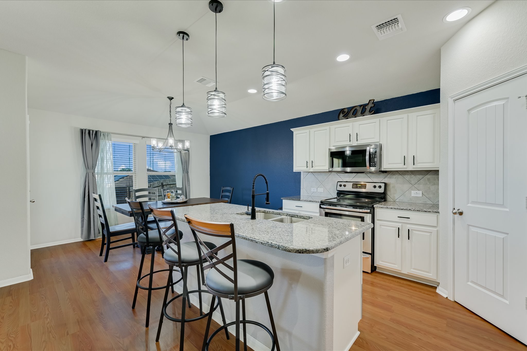 725 Pinnacle Drive Georgetown, TX 78626 - Photo 6 of 20 a kitchen with stainless steel appliances granite countertop a stove a refrigerator a kitchen island a sink and a refrigerator with wooden floor