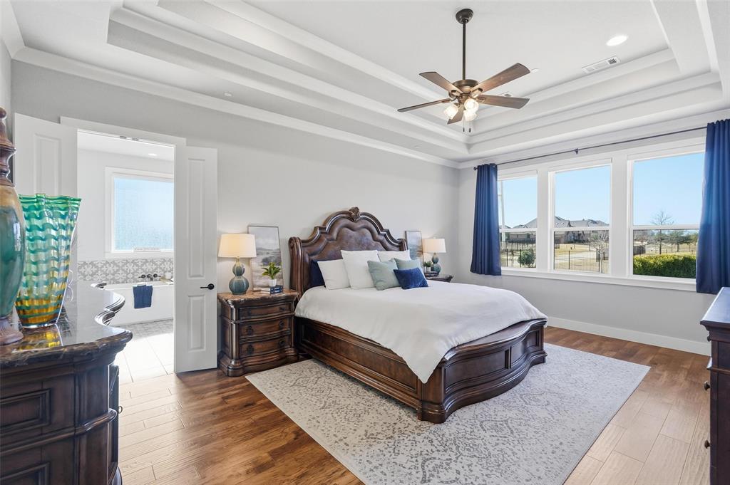 640 Maggie Trail Lucas, TX 75002 - Photo 18 of 40 a spacious bedroom with a large bed and a chandelier