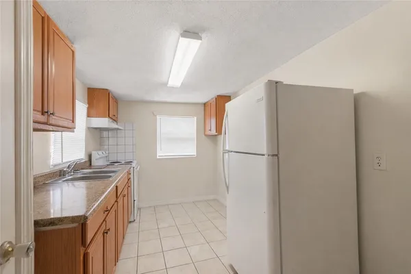 a kitchen with a sink a refrigerator and a stove top oven