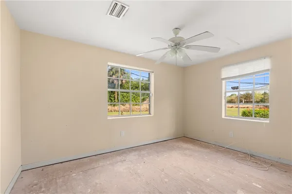 an empty room with windows and fan