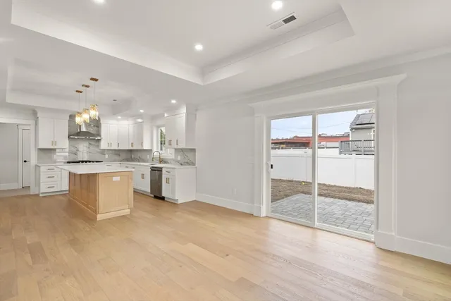 a large kitchen with stainless steel appliances kitchen island a large counter top and a wooden floors