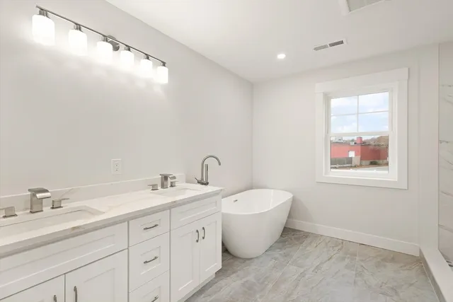 a bathroom with a white tub a sink and mirror
