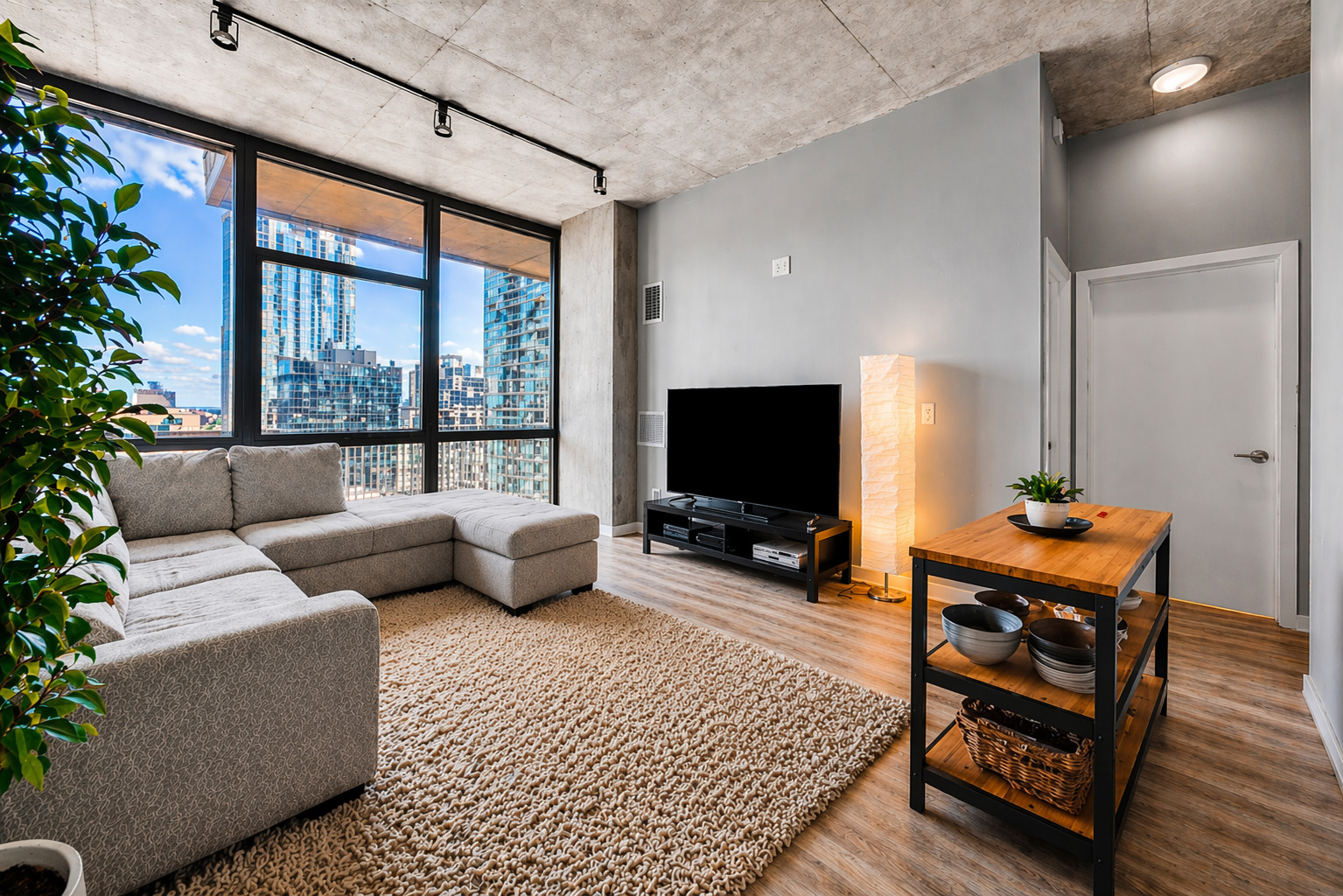 235 West Van Buren Street, Unit 2513 Chicago, IL 60607 - Photo 4 of 18 a living room with furniture a flat screen tv and a floor to ceiling window