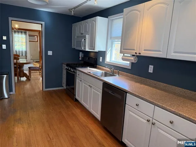 a kitchen with stainless steel appliances granite countertop a sink a stove and cabinets