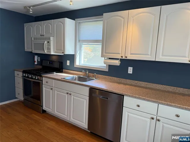 a kitchen with granite countertop white cabinets and black appliances