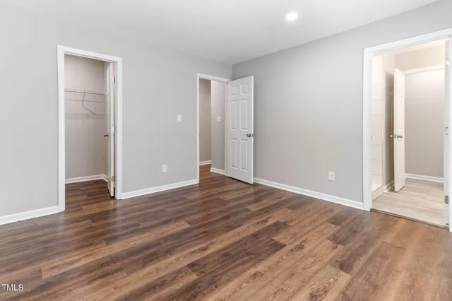 an empty room with wooden floor & closet area