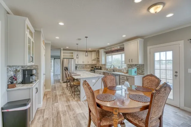 a kitchen with a dining table chairs stainless steel appliances and cabinets