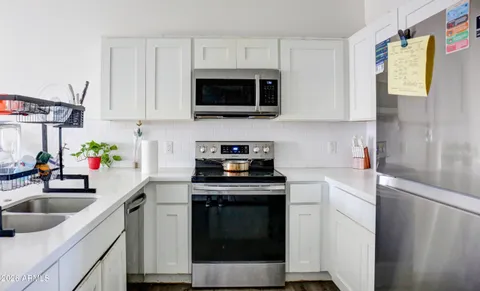 a kitchen with stainless steel appliances white cabinets a sink a stove and a refrigerator