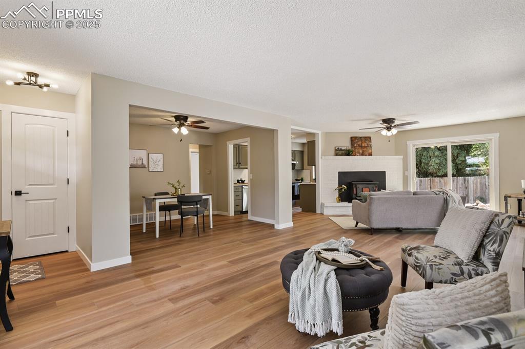 79 Old Broadmoor Road Colorado Springs, CO 80906 - Photo 11 of 27 Living room with ceiling fan, light wood finished floors, a textured ceiling, and a fireplace