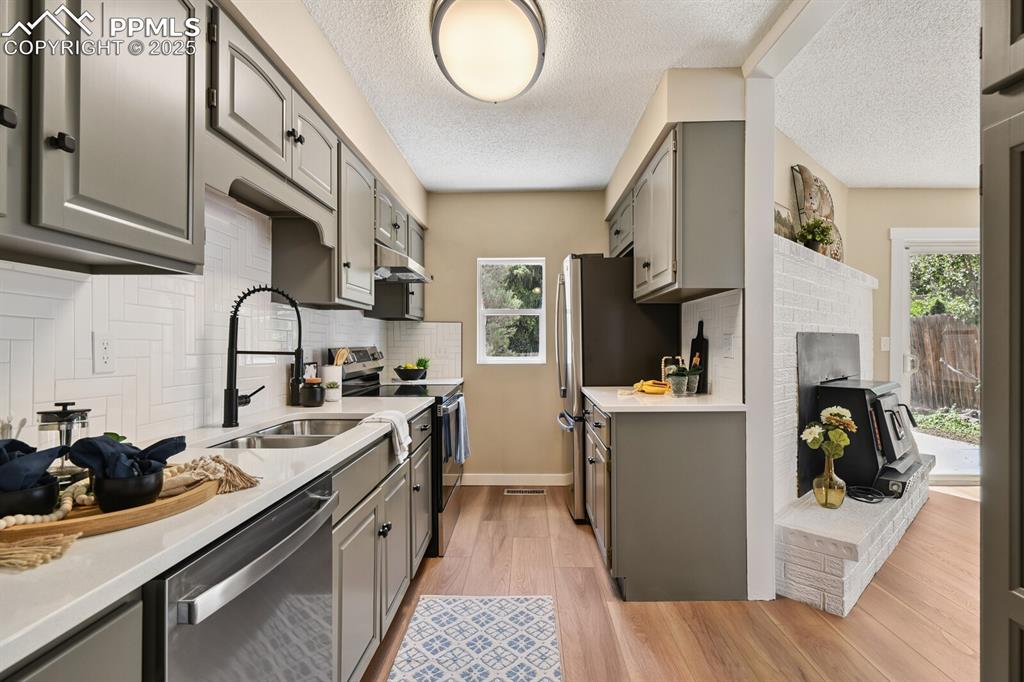 79 Old Broadmoor Road Colorado Springs, CO 80906 - Photo 14 of 27 Kitchen with stainless steel appliances, gray cabinets, light countertops, light wood finished floors, and a textured ceiling