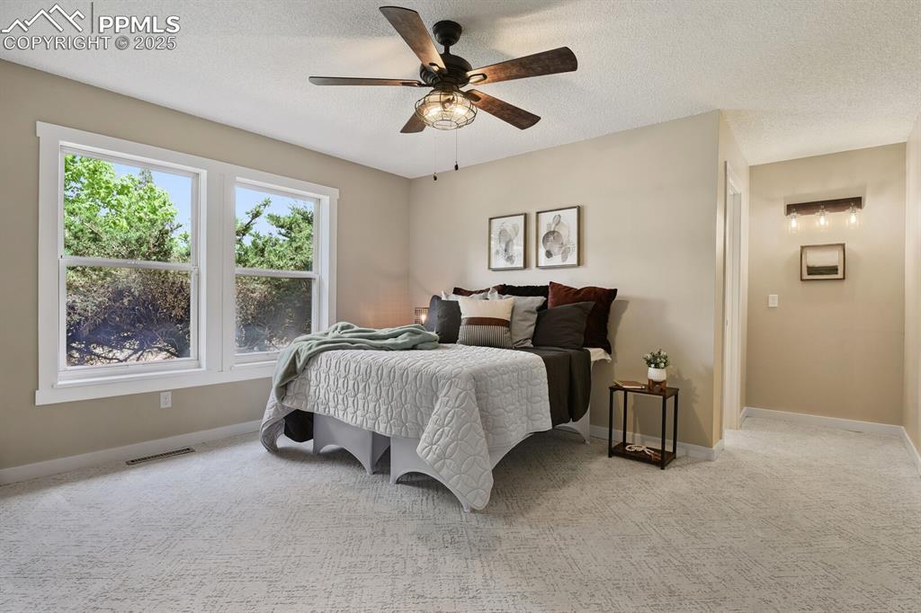 79 Old Broadmoor Road Colorado Springs, CO 80906 - Photo 17 of 27 Bedroom with light colored carpet, a ceiling fan, and a textured ceiling