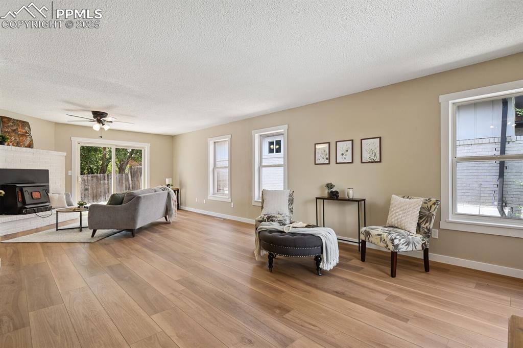 79 Old Broadmoor Road Colorado Springs, CO 80906 - Photo 5 of 27 Living room with a textured ceiling, light wood finished floors, ceiling fan, and a wood stove