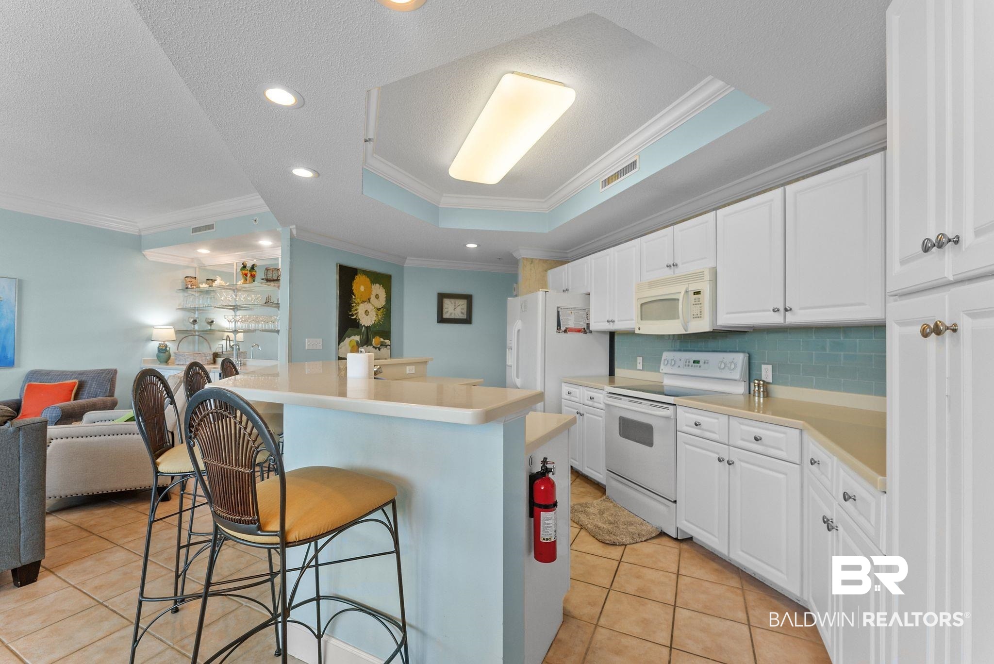 27580 Canal Road, Unit 1427 Orange Beach, AL 36561 - Photo 21 of 38 Kitchen featuring light countertops, ornamental molding, white cabinetry, a kitchen bar, and white appliances
