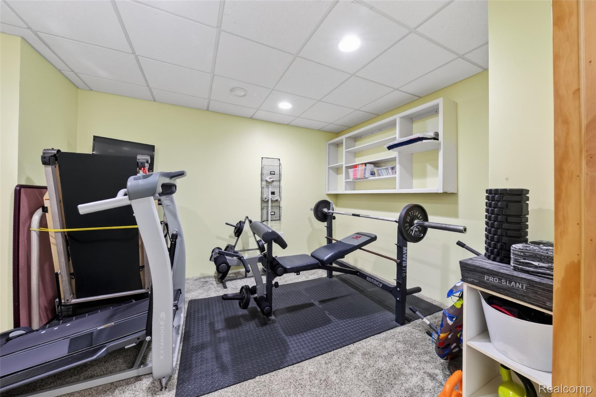 7447 Ore Lake Road Brighton, MI 48116 - Photo 44 of 45 Recessed ceiling lighting illuminates a dedicated fitness area featuring light-toned walls, textured carpeting, and a drop ceiling