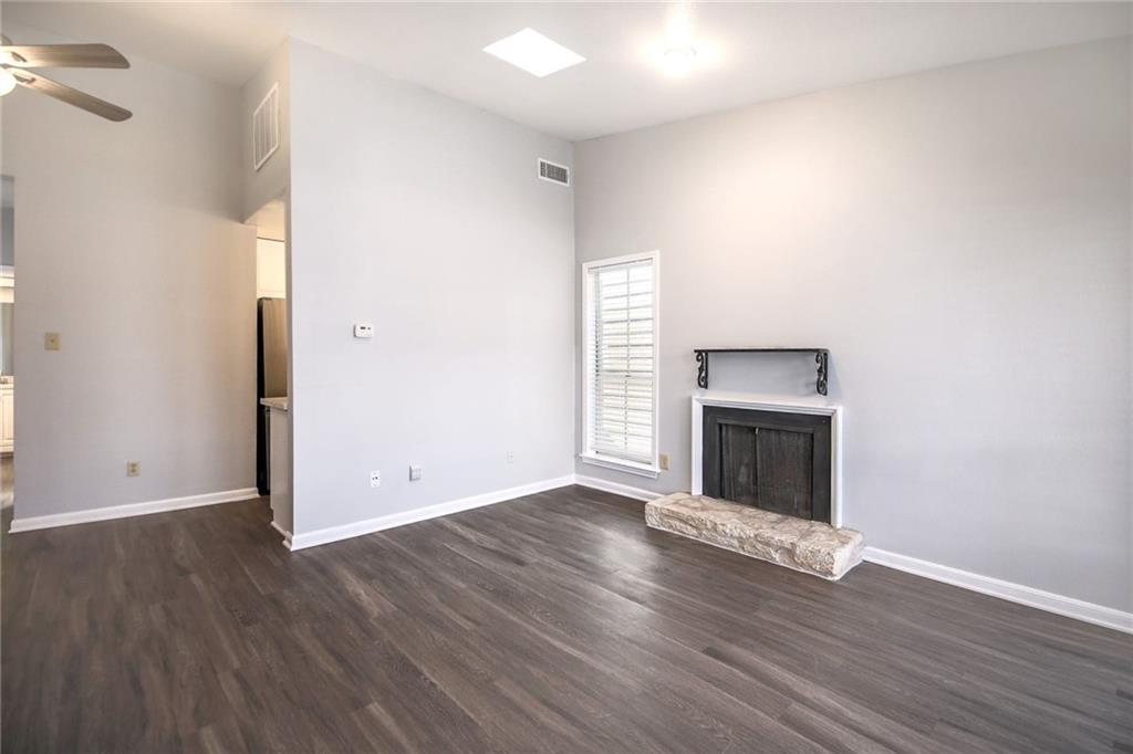2529 Rio Grande Street, Unit 93 Austin, TX 78705 - Photo 8 of 19 This living area features wood flooring, light-colored walls, a ceiling fan, and a fireplace with a stone hearth