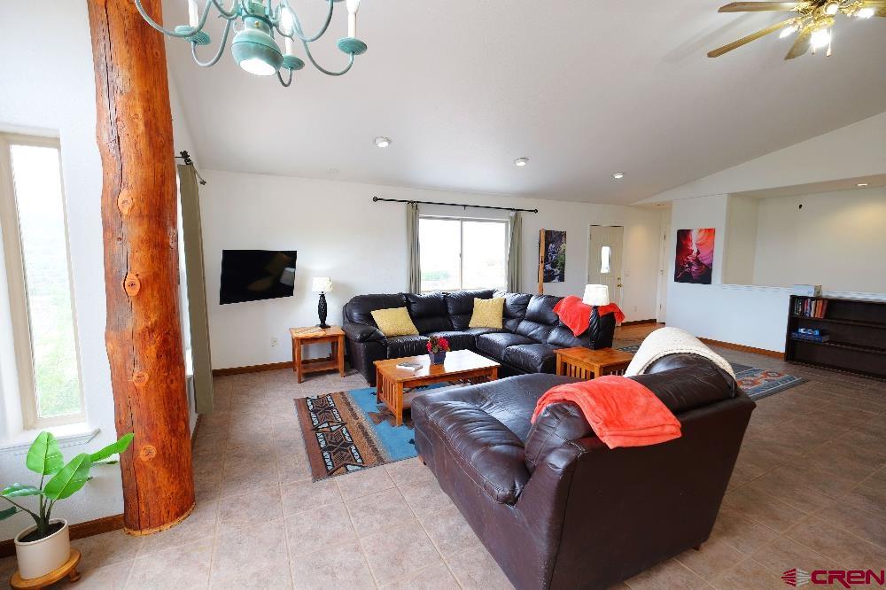 14135 N73 Road Montrose, CO 81401 - Photo 5 of 29 a living room with furniture a chandelier and a flat screen tv