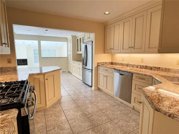 a kitchen with granite countertop a refrigerator and a stove top oven