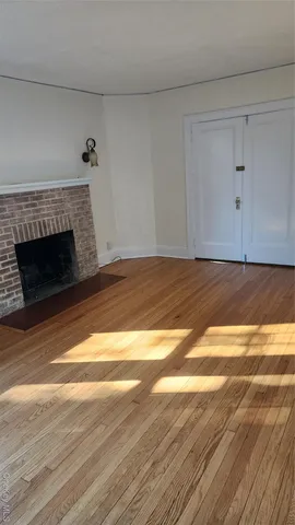 a view of an empty room with wooden floor and a fireplace