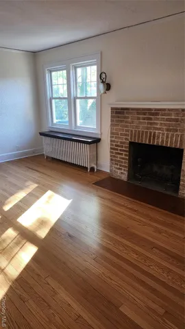 an empty room with wooden floor fireplace and windows