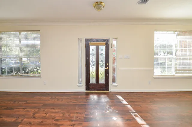 a view of an empty room with wooden floor and a window